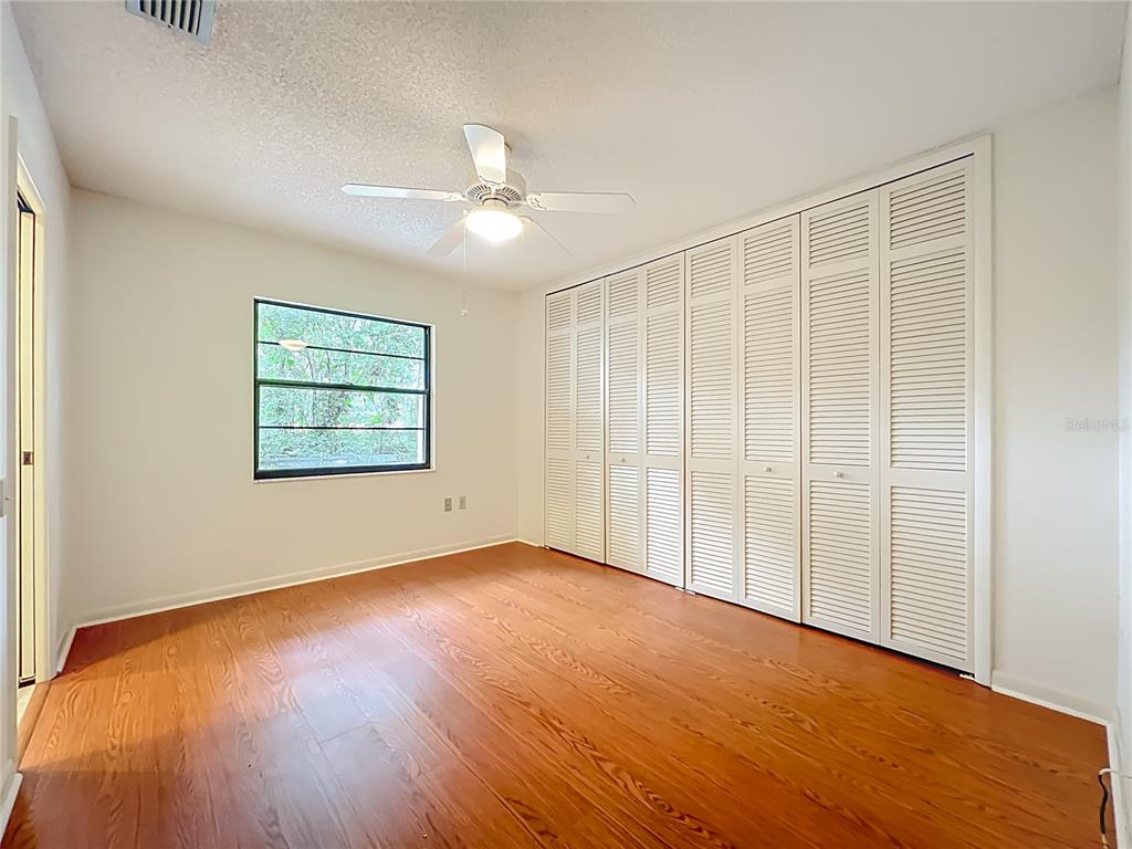 1942 Country Club Road Eustis, FL 32726 - Photo 25 of 56 an empty room with wooden floor chandelier fan and windows