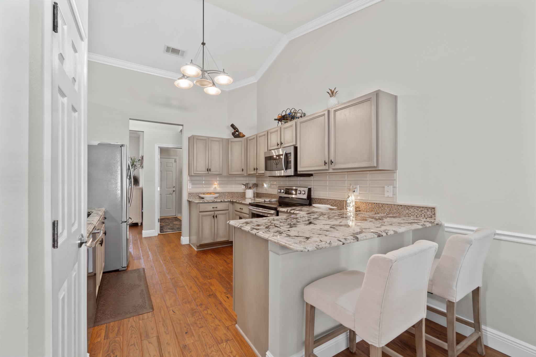 99 Inlet Drive Santa Rosa Beach, FL 32459 - Photo 10 of 52 a kitchen with stainless steel appliances granite countertop a refrigerator a sink dishwasher a stove and white cabinets with wooden floor