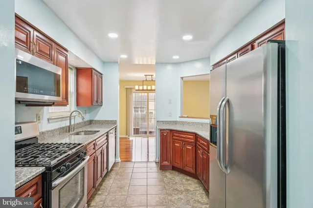a kitchen with stainless steel appliances granite countertop a refrigerator and a stove top oven