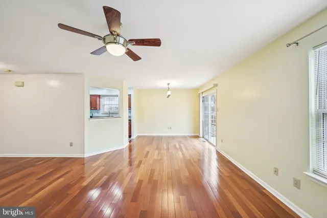 a view of empty room with wooden floor and fan