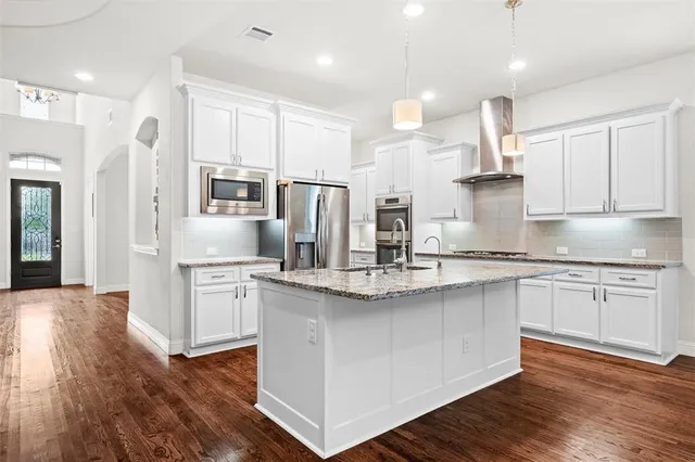 a kitchen with stainless steel appliances granite countertop a white cabinets and wooden floor