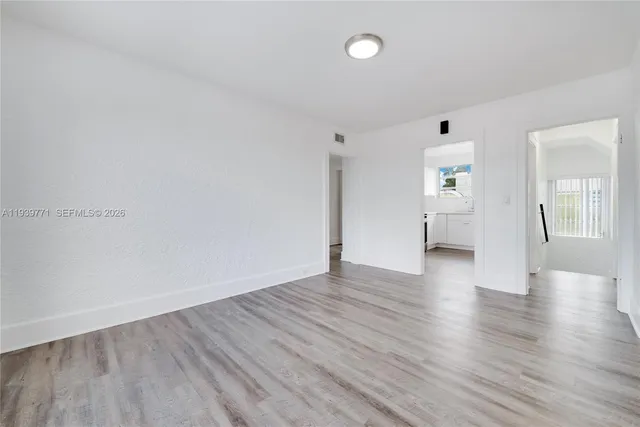 a view of an empty room with wooden floor and a window