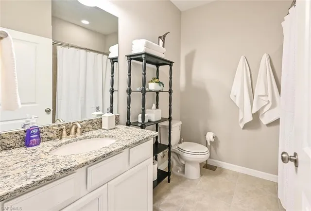 a bathroom with a granite countertop sink mirror vanity and toilet