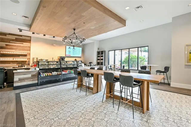 a room with lots of tables a large window and chairs