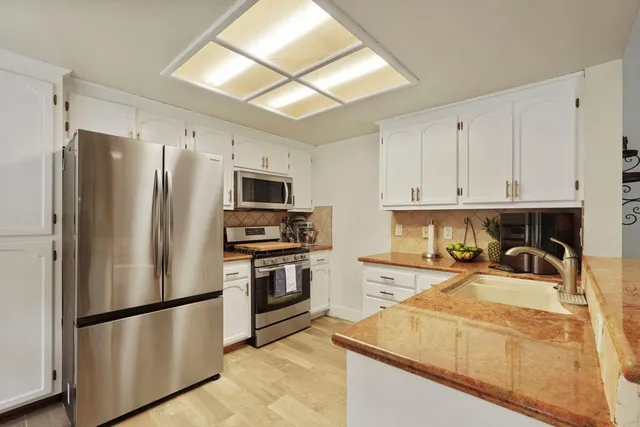 a kitchen with stainless steel appliances granite countertop a refrigerator stove top oven and sink