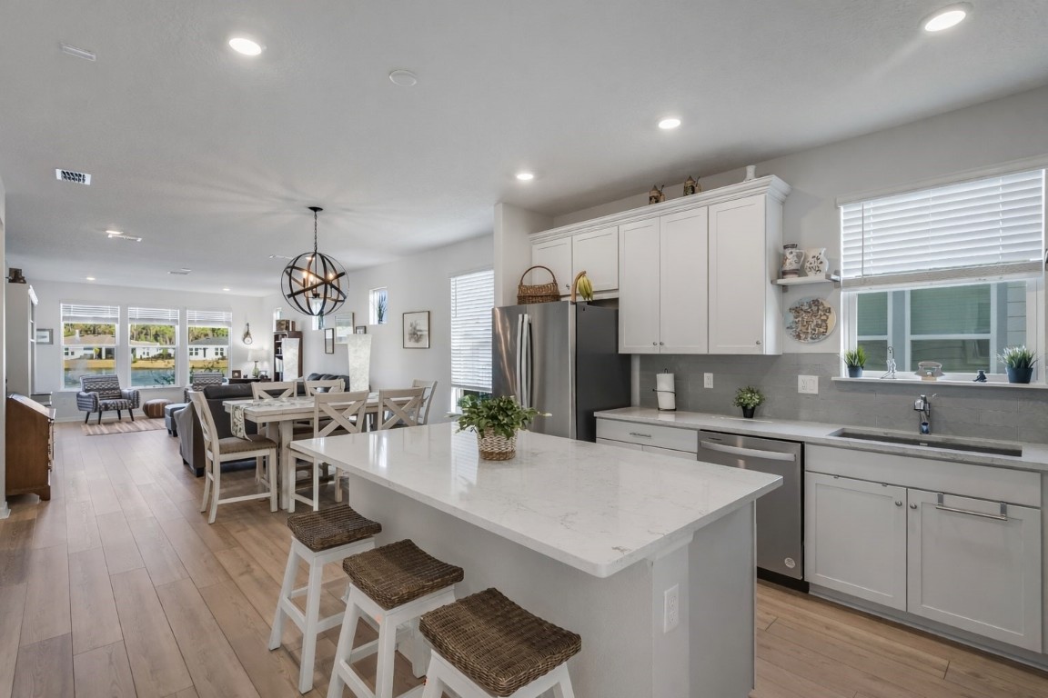 727 Cool Breeze Way Yulee, FL 32097 - Photo 3 of 34 a kitchen with a dining table chairs sink and white appliances