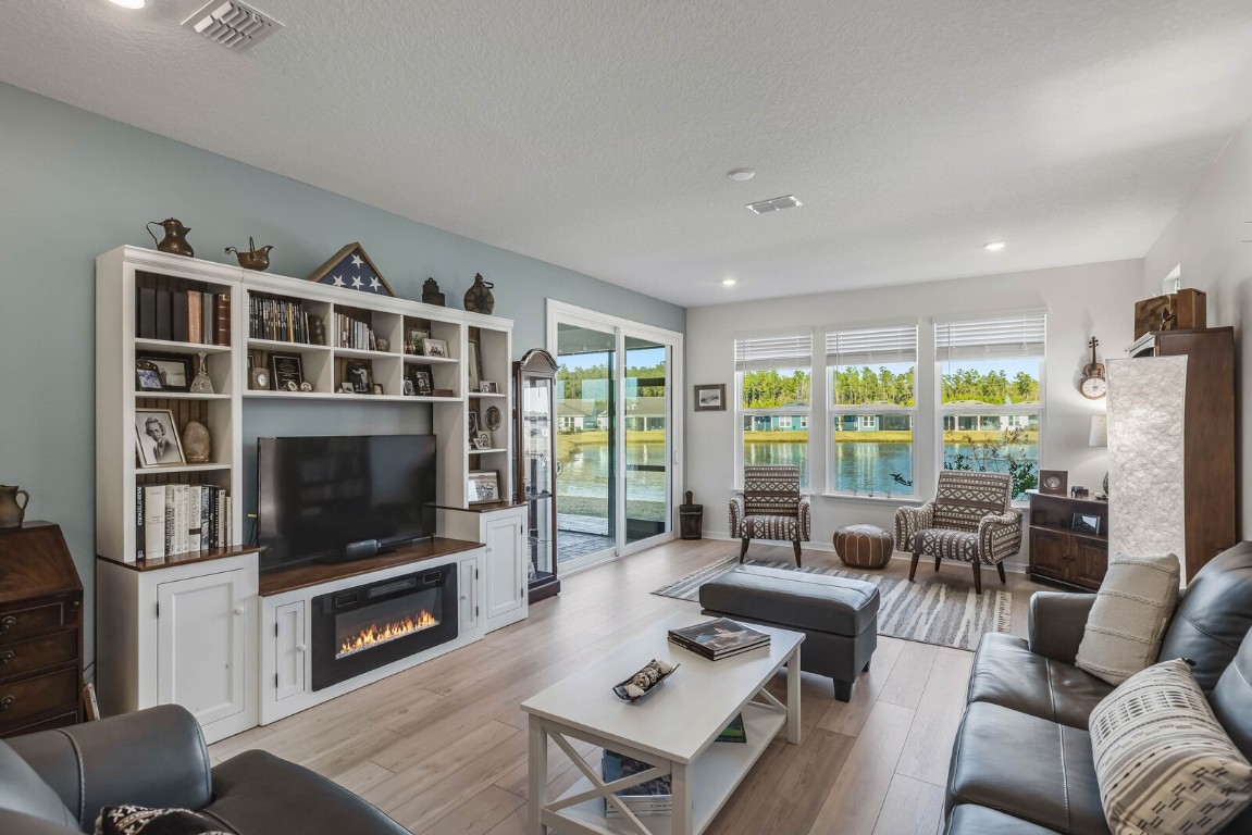 727 Cool Breeze Way Yulee, FL 32097 - Photo 7 of 34 a living room with furniture a flat screen tv and a floor to ceiling window