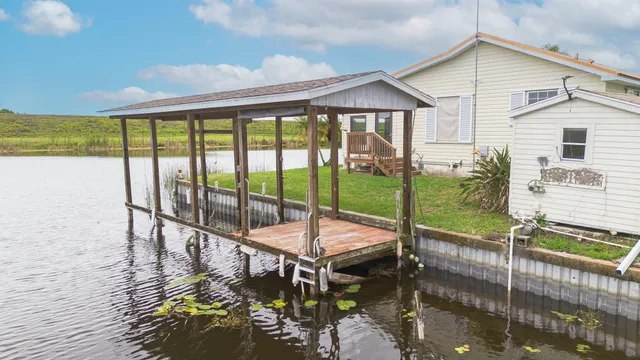 a view of a livingroom with furniture wooden floor a kitchen view and a chandelier
