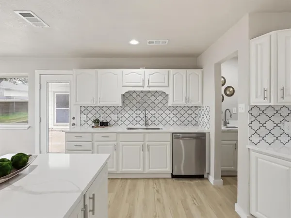 a kitchen with white cabinets a sink a window and appliances