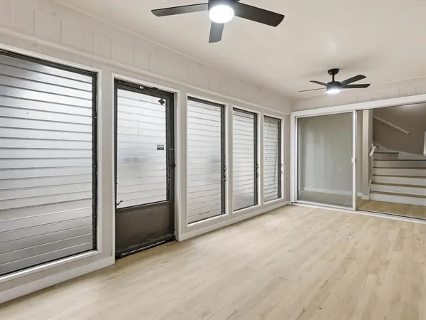 a view of an empty room with wooden floor and window