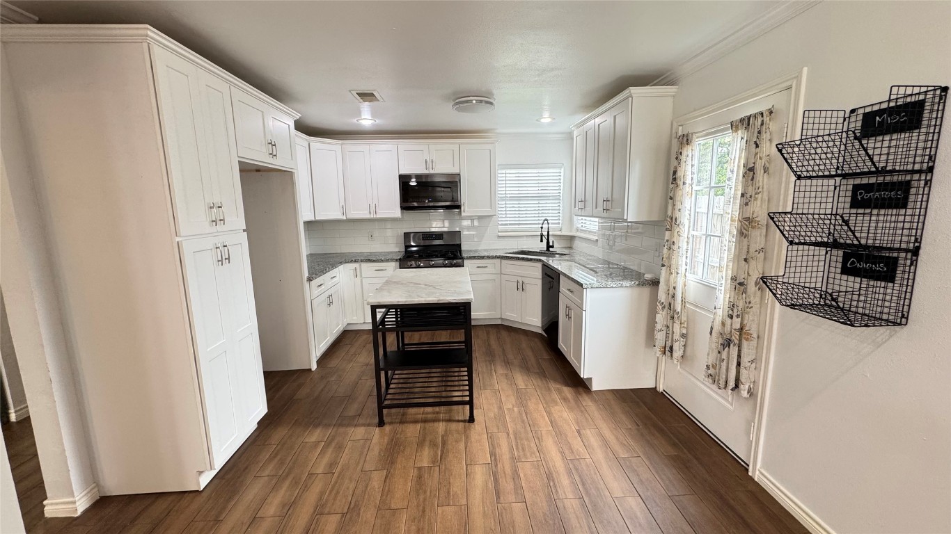 221 Hyta Street Houston, TX 77018 - Photo 7 of 35 a kitchen with stainless steel appliances a stove top oven a sink a refrigerator white cabinets and wooden floor