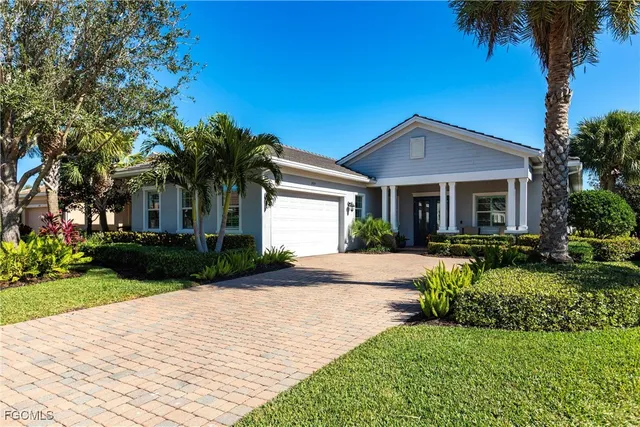 a front view of a house with a garden and palm trees