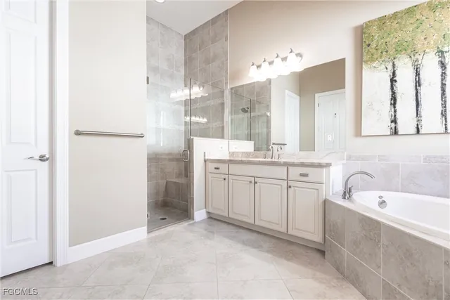 a spacious bathroom with a double vanity sink a mirror a bathtub and shower