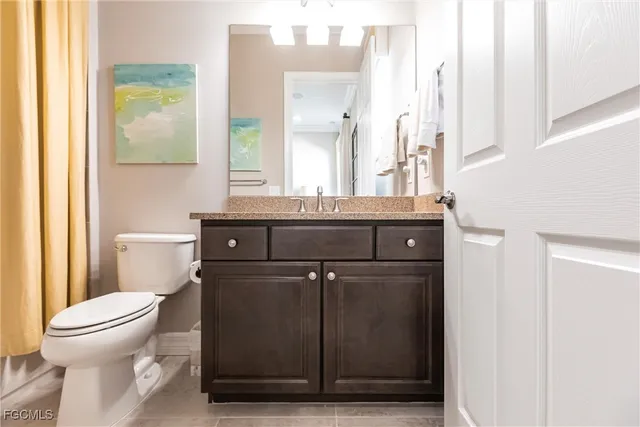 a bathroom with a granite countertop sink a toilet and a mirror