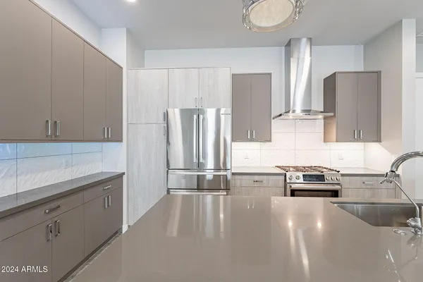 a large white kitchen with kitchen island a sink stainless steel appliances and a counter top