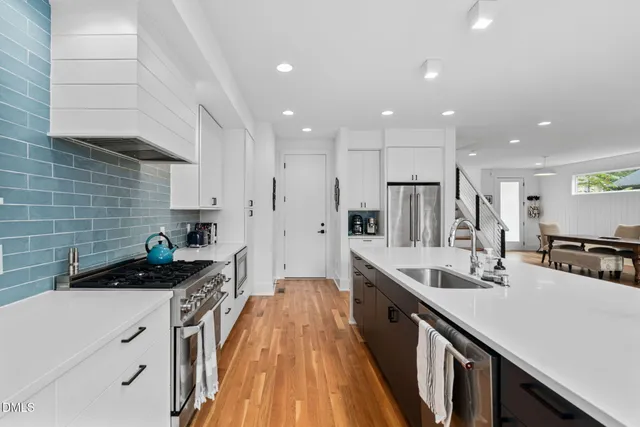 a kitchen with a dining table chairs wooden floor appliances and cabinets