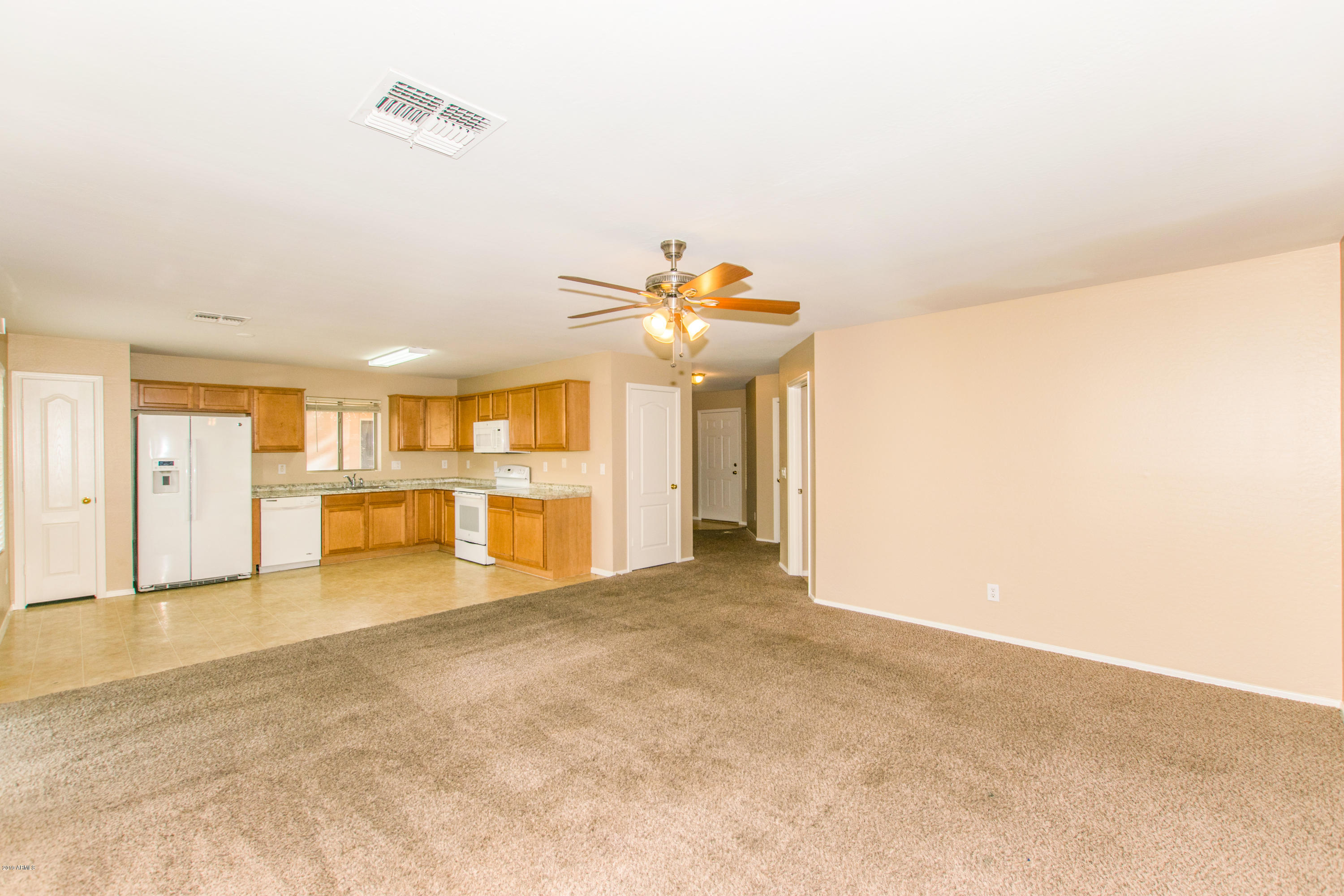 43750 West Magnolia Road Maricopa, AZ 85138 - Photo 5 of 28 a view of a livingroom with a flat screen tv and kitchen space