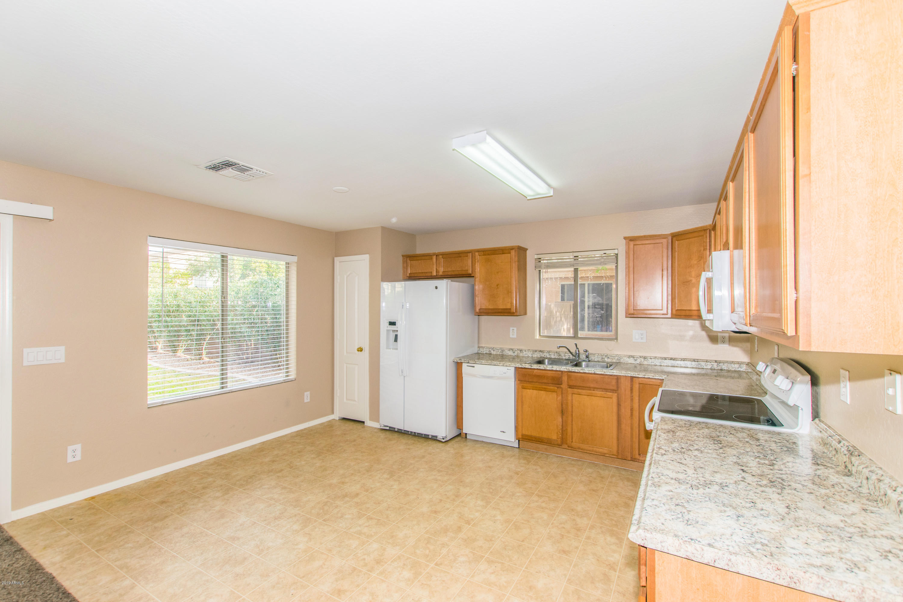 43750 West Magnolia Road Maricopa, AZ 85138 - Photo 7 of 28 a large kitchen with kitchen island a large window a sink and stainless steel appliances