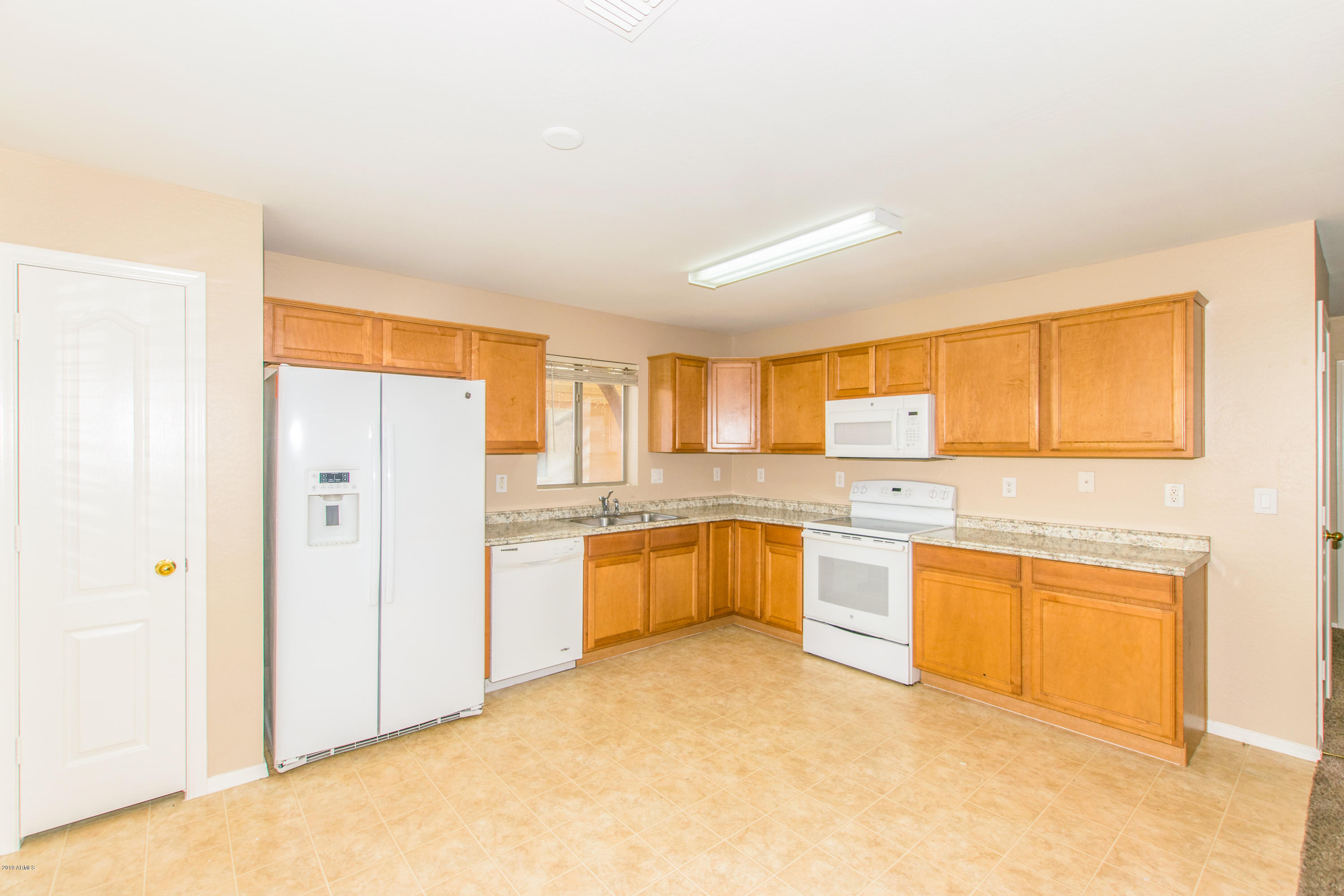 43750 West Magnolia Road Maricopa, AZ 85138 - Photo 8 of 28 a large white kitchen with cabinets a sink a window and a refrigerator