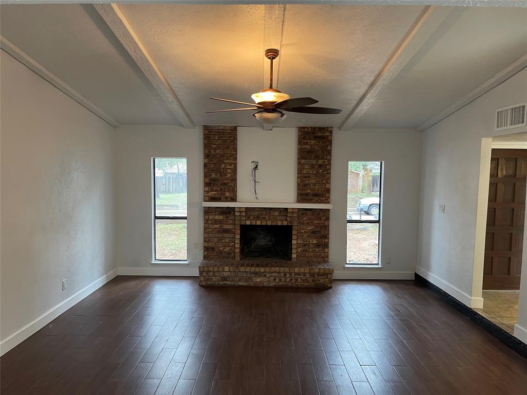 3732 Pinewood Street Bedford, TX 76021 - Photo 3 of 18 an empty room with wooden floor fireplace and windows