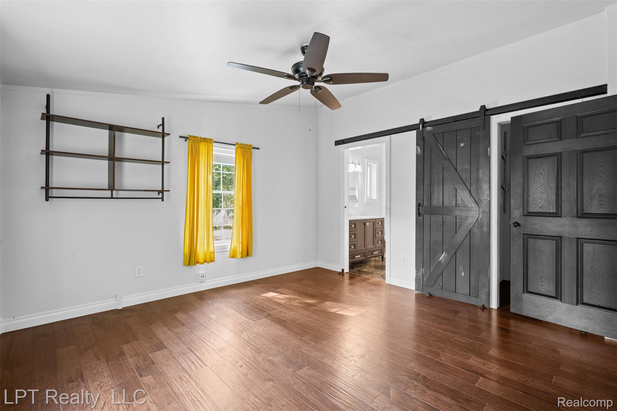6271 East Potter Road Davison, MI 48423 - Photo 14 of 41 Unfurnished bedroom with hardwood / wood-style flooring, a ceiling fan, ensuite bathroom, and a barn door