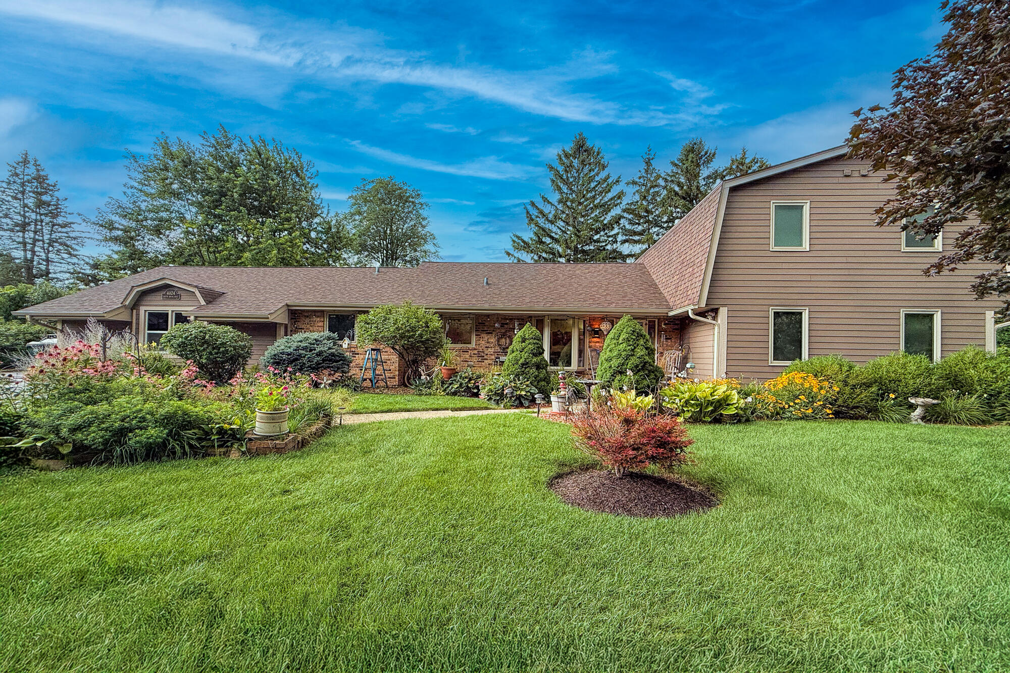 4024 South Brook Road Caledonia, WI 53126 - Photo 56 of 66 Front view of home in summer with lush bushes