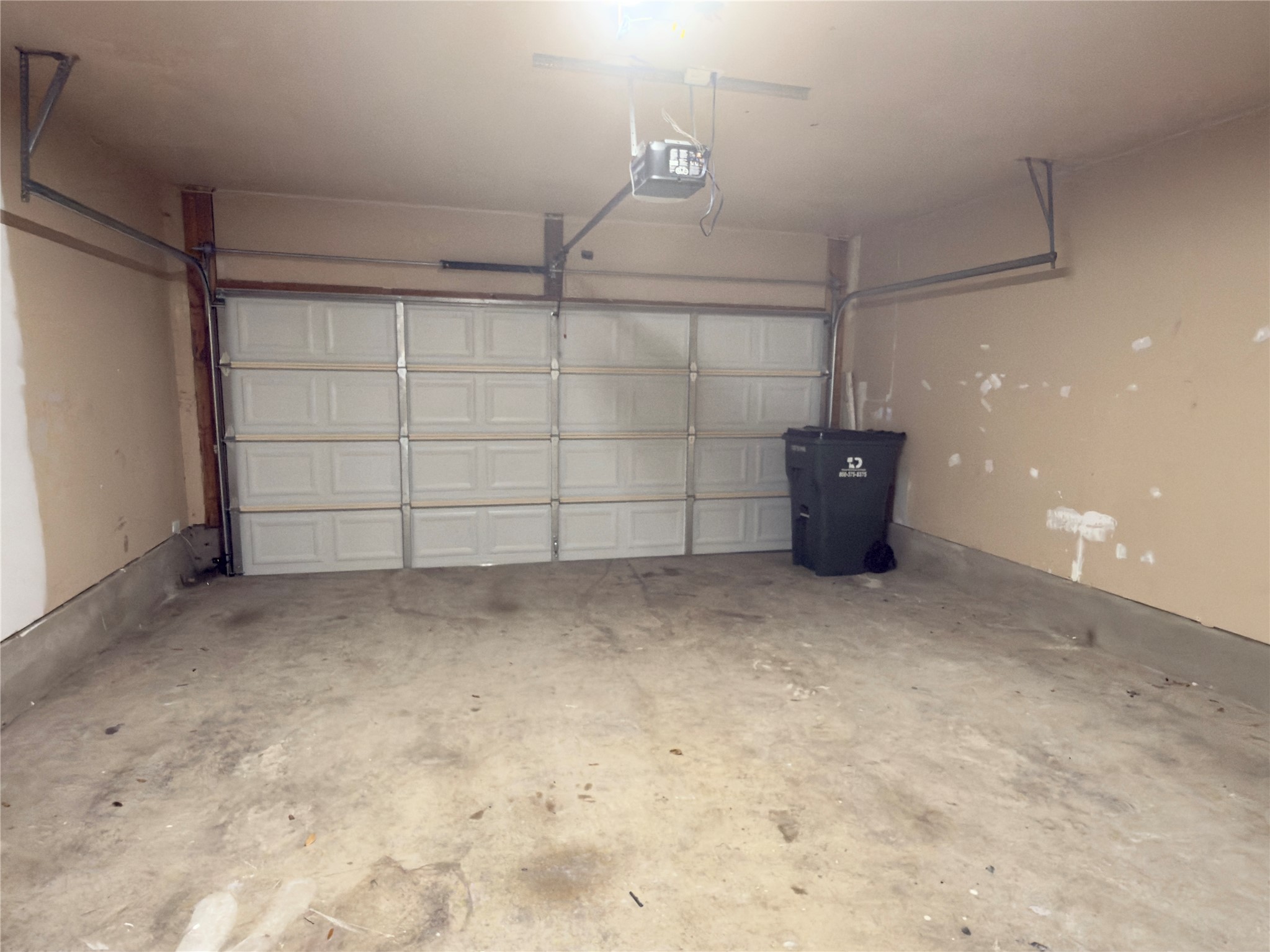 255 Myrtle Street Kyle, TX 78640 - Photo 28 of 31 Single-car garage with a paneled overhead door, concrete flooring, and an exposed garage door opener mechanism