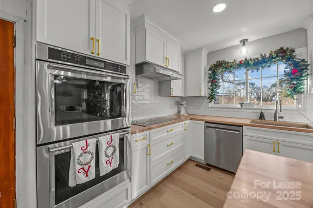 a kitchen with stainless steel appliances granite countertop a stove and white cabinets
