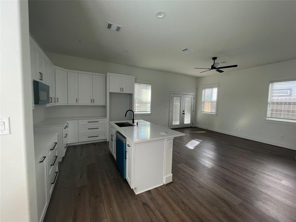3535 Spring Avenue Dallas, TX 75210 - Photo 19 of 19 Kitchen with white cabinetry, an island with sink, dark wood-style flooring, open floor plan, and black microwave