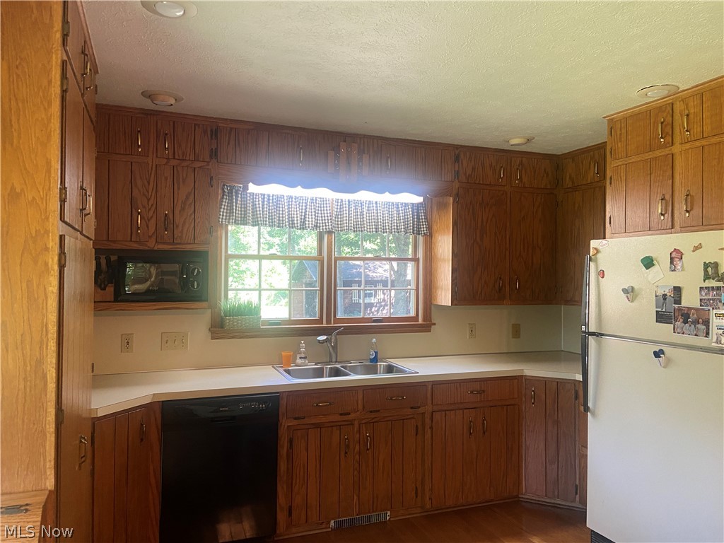 2445 South Elyria Road Wooster, OH 44691 - Photo 11 of 46 Kitchen featuring freestanding refrigerator, dishwasher, light countertops, wood finished floors, and brown cabinets