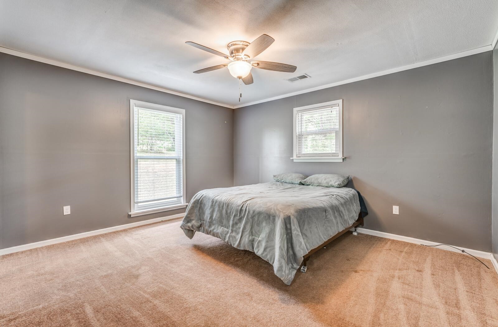 6125 Warren Road Oakland, TN 38060 - Photo 30 of 40 Spacious room featuring neutral gray walls, crown molding, two windows with white blinds, and a ceiling fan with light fixture