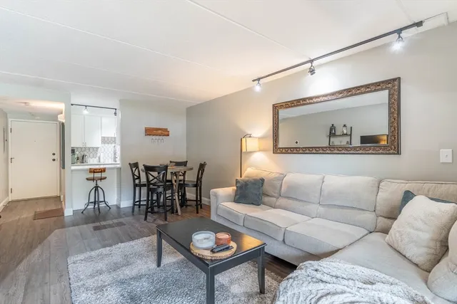 a living room with furniture a rug and kitchen view