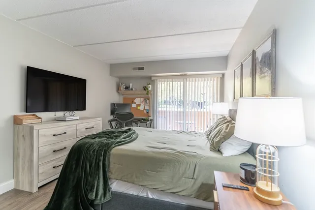 a bedroom with a bed and a flat tv screen on dresser