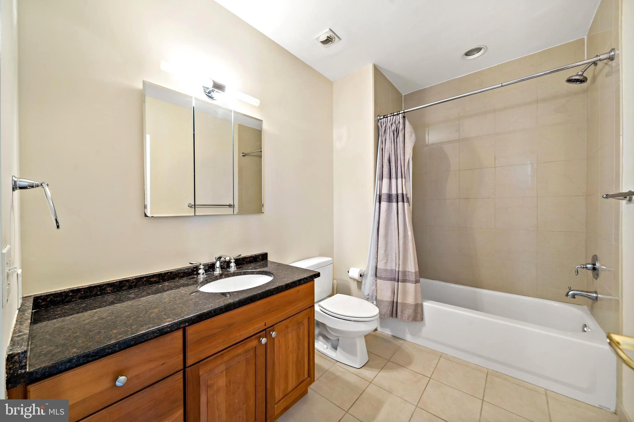1600 Arch Street, Unit 1116 Philadelphia, PA 19103 - Photo 9 of 23 a bathroom with a granite countertop sink a toilet a mirror and shower
