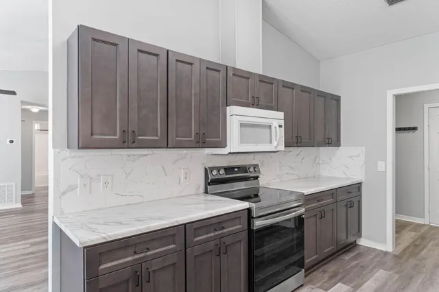 a kitchen with granite countertop a sink cabinets and stainless steel appliances