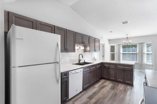 a kitchen with a sink a refrigerator a window and cabinets