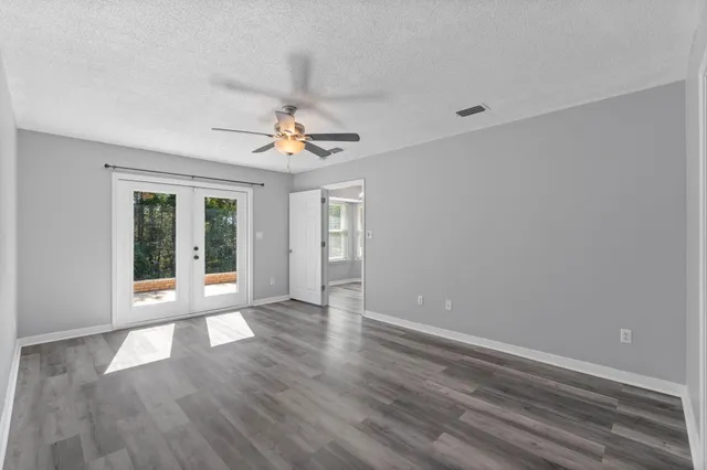 a view of an empty room with a window and wooden floor