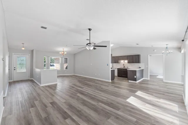 a view of a kitchen with kitchen island a sink wooden floor and a refrigerator