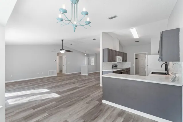 a view of a kitchen with a sink dishwasher a refrigerator and a fireplace with wooden floor