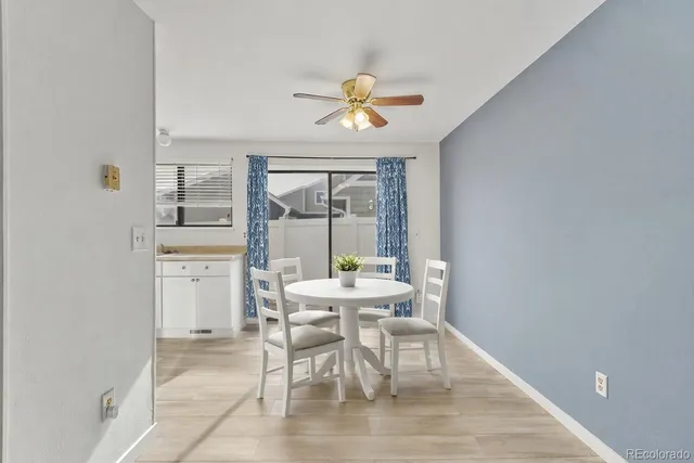 a dining room with wooden floor a chandelier fan a wooden table and chairs