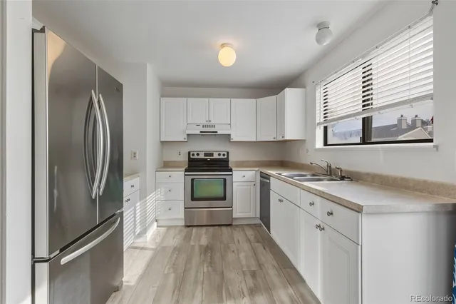 a kitchen with granite countertop a refrigerator stove and sink