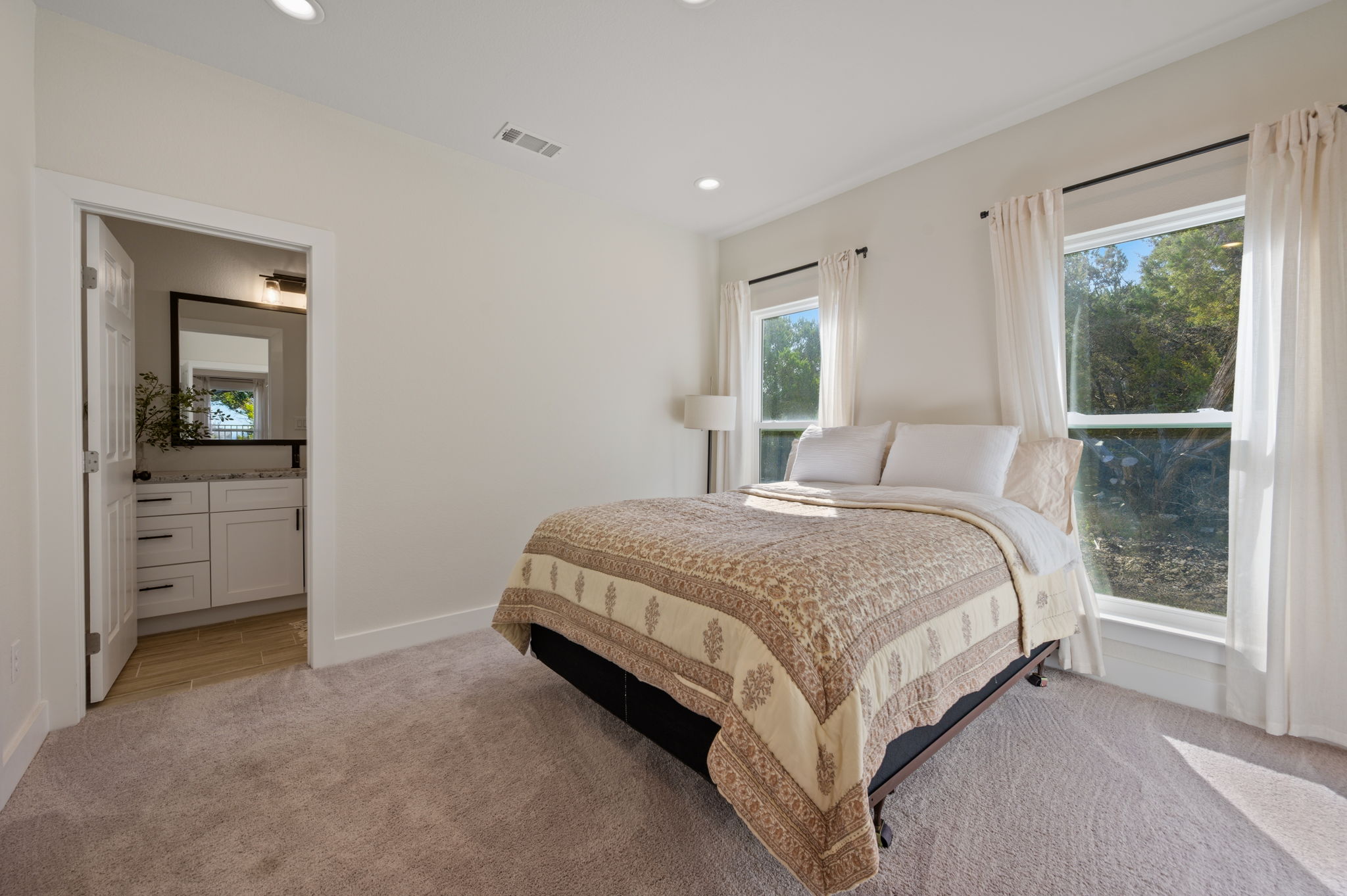 8604 Bar K Ranch Road Lago Vista, TX 78645 - Photo 22 of 37 Bedroom with light carpet, multiple windows, recessed lighting, and ensuite bath