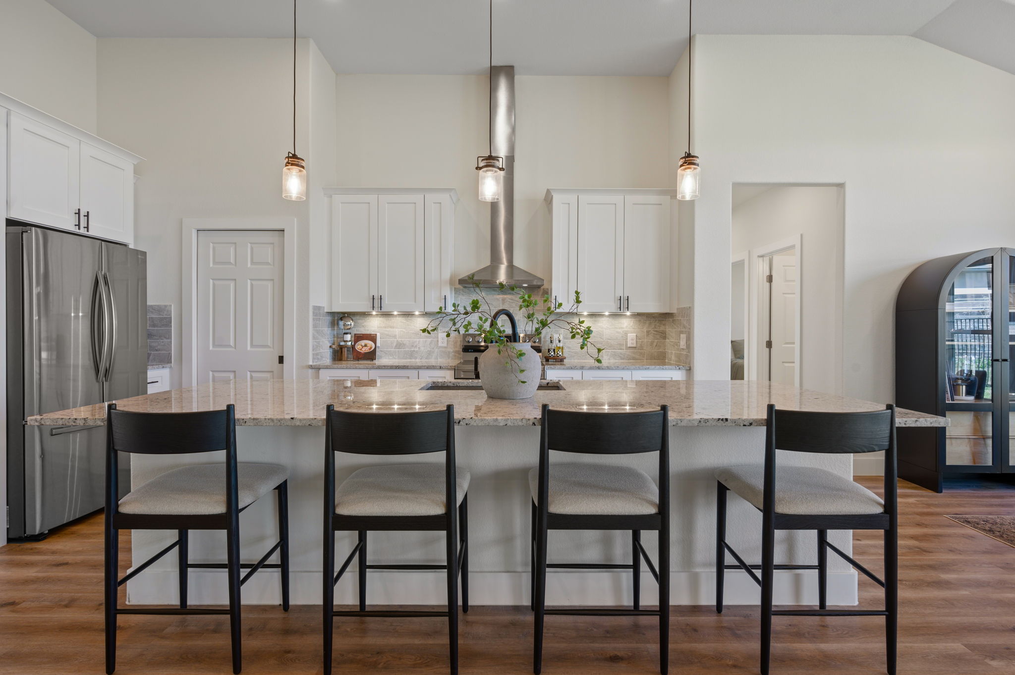 8604 Bar K Ranch Road Lago Vista, TX 78645 - Photo 6 of 37 Kitchen featuring freestanding refrigerator, white cabinets, light wood-style floors, light stone countertops, and pendant lighting