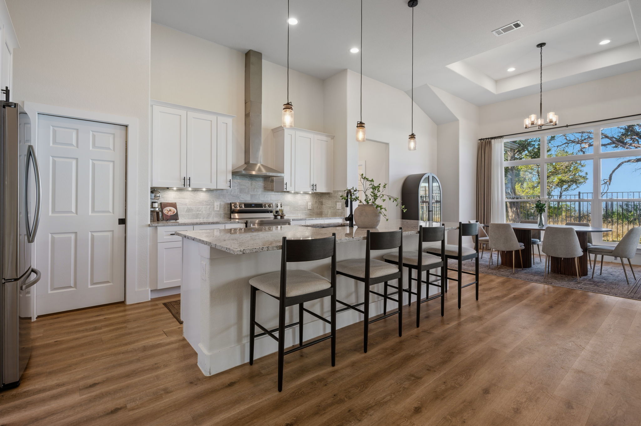 8604 Bar K Ranch Road Lago Vista, TX 78645 - Photo 7 of 37 Kitchen featuring a kitchen bar, light stone counters, a high tray ceiling, stainless steel appliances, and a kitchen island with sink