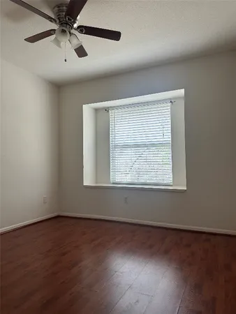 an empty room with wooden floor fan and windows
