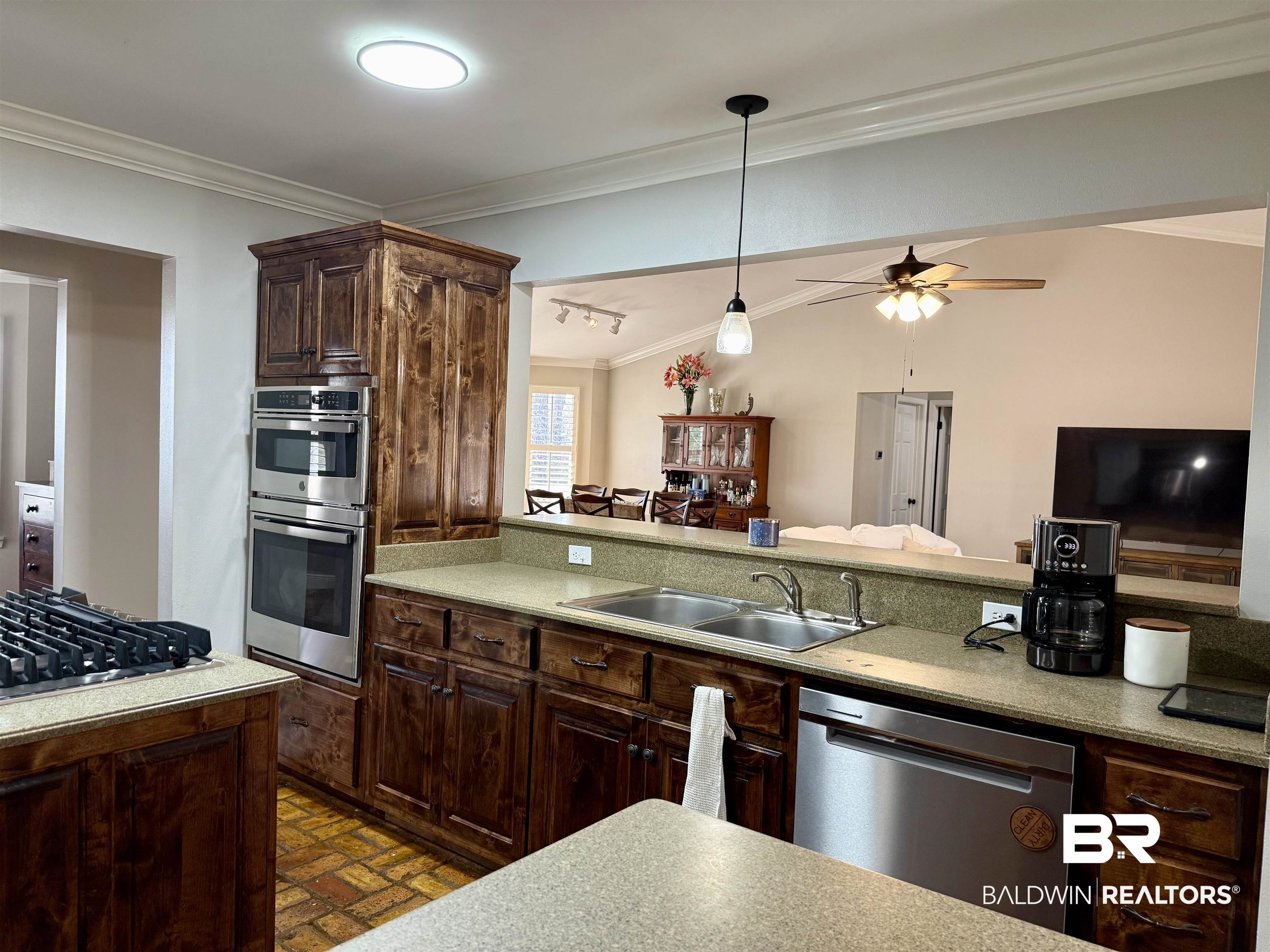 5646 Foshee Road Brewton, AL 36426 - Photo 37 of 37 Kitchen featuring dark wood finish cabinets, crown molding, stainless steel appliances, open floor plan, and brick patterned floors