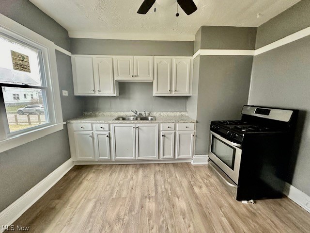 972 Paxton Road Cleveland, OH 44108 - Photo 10 of 22 Kitchen with ceiling fan, sink, light hardwood / wood-style floors, stainless steel gas stove, and white cabinets