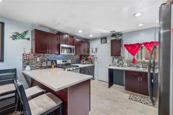 a kitchen with stainless steel appliances granite countertop a stove refrigerator sink dining table and chairs