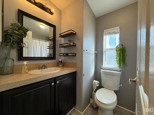 a bathroom with a granite countertop toilet sink and mirror