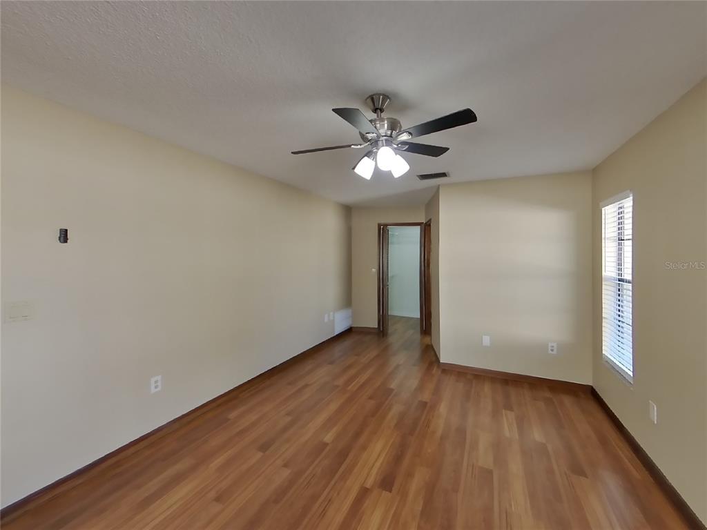 Undisclosed Address Spring Hill, FL 34608 - Photo 6 of 16 a view of an empty room with wooden floor and a window